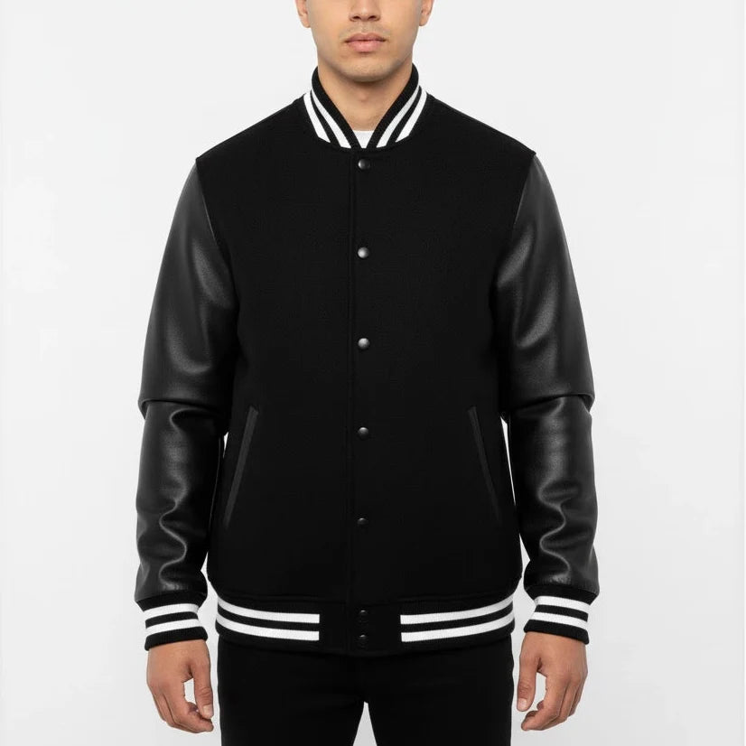 Man wearing a black varsity jacket with leather sleeves on a white background