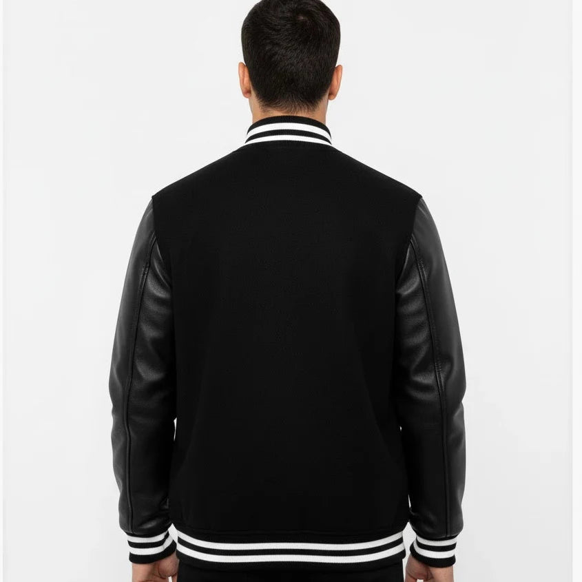 Person wearing a black varsity jacket with leather sleeves on a white background