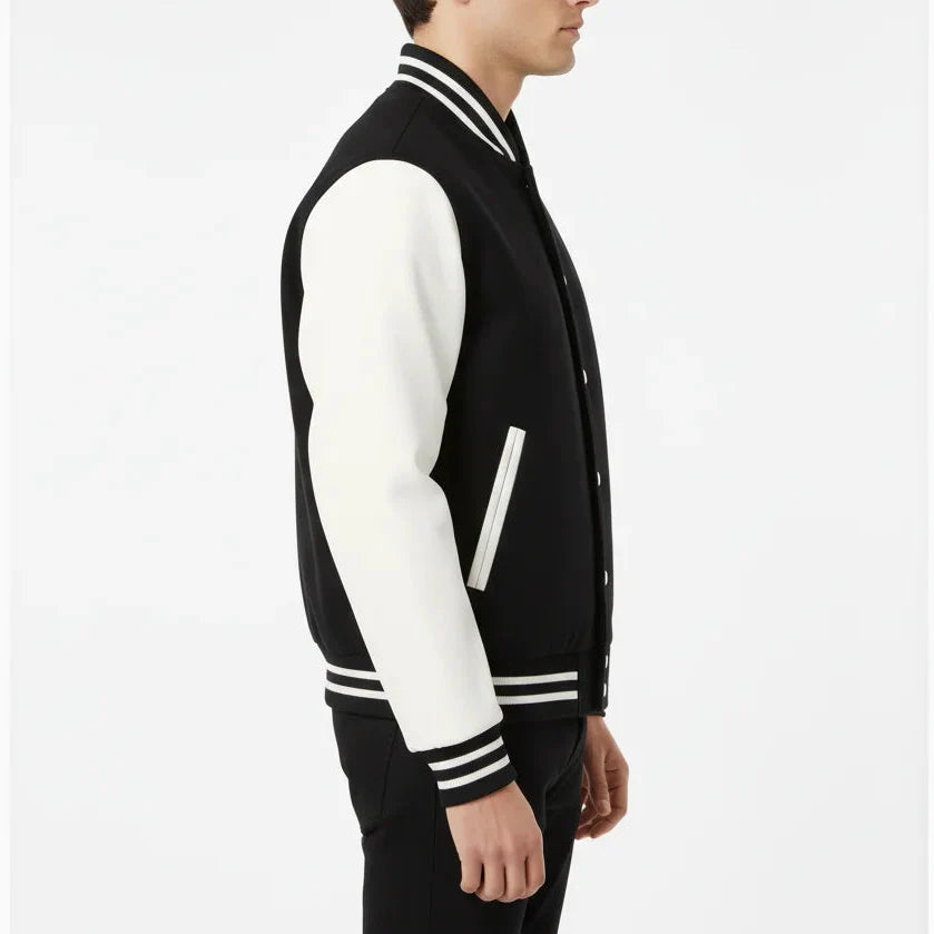 Man wearing a black and white varsity jacket on a light gray background