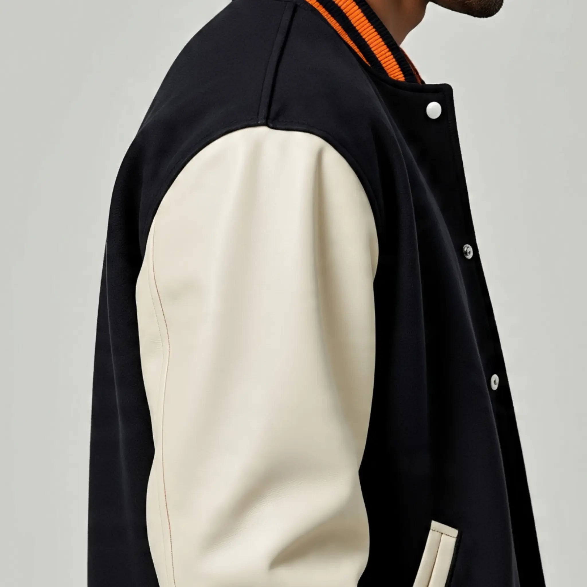 Black and beige varsity jacket on a plain background