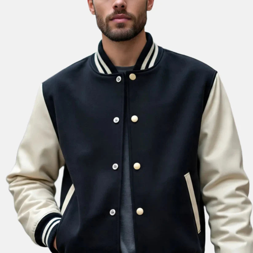 Man wearing a black and beige varsity jacket on a plain background